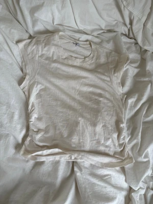 Benvit T-shirt med scrunch  - T-shirt i mjuk bomull med rund halsringning. Toppen har en enkel och clean design med lätt figurnära passform och diskreta sömmar vid axlarna. Basic och går att matcha med mycket 