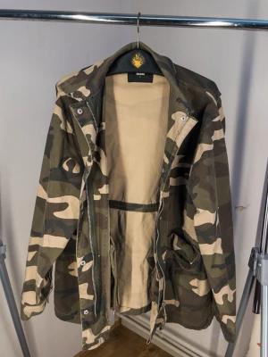 Camouflage Jacka - riktigt snygg camouflage jacka i bra skick från Bikbok i storlek L. stängs med dragkedja och knappar, även justerbar i midjan som du ser på bild nr 5!