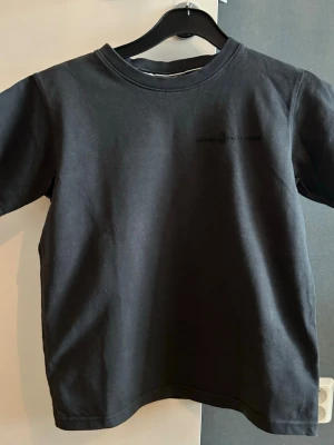 Svart t-shirt från Sail Racing  - Svart t-shirt från Sail Racing med diskret logga på bröstet. T-shirten har rund hals och korta ärmar. En modell med kortare längd