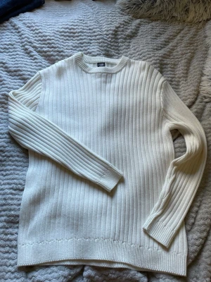 Vit ribbstickad tröja - Säljer en stilren vit ribbstickad tröja. Tröjan har rund halsringning, långa ärmar och är gjord i ett mjukt stickat material. Perfekt för dig som gillar klassiska och minimalistiska plagg. Pris går att diskutera!
