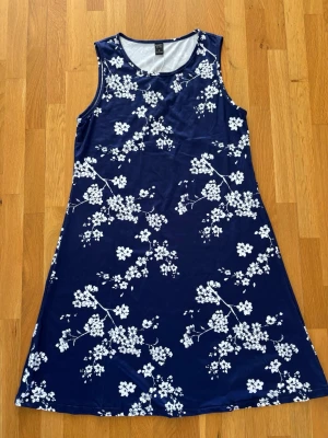 Blommig sommarklänning - Säljer en fin sommarklänning i mörkblått med vitt blommönster. Klänningen är ärmlös med rund halsringning och har en lätt A-linjeform som faller fint och är bekväm att bära. Perfekt till vardags, semester eller sommarens tillfällen. 