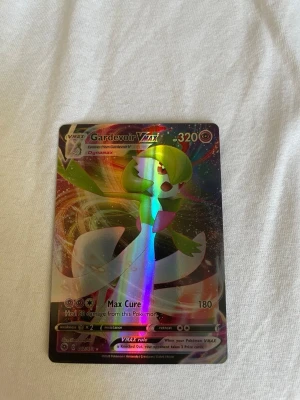 Gardevoir VMAX Pokémonkort holo - Säljer ett Gardevoir VMAX Pokémonkort med holografisk yta. Kortet har färger i grönt, vitt och rosa med glittriga detaljer och är perfekt för samlare eller Pokémonfans. Kortet har 320 HP och coolt motiv från Dynamax-serien.
