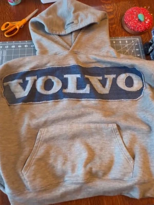 Hand gjord Volvo-tröja - Säljer en grå hoodie med handgjord Volvo logga som är stilren och unik med en vintage look. Använder en likadan och aldrig fått så mycket komplimanger av ett plagg. finns i alla storlekar görs på beställning just denna är st XS/S. säljer även BMW, Mercedes, Volkswagen, Audi i samma stilrena vintage look. Helt ny hoodie!