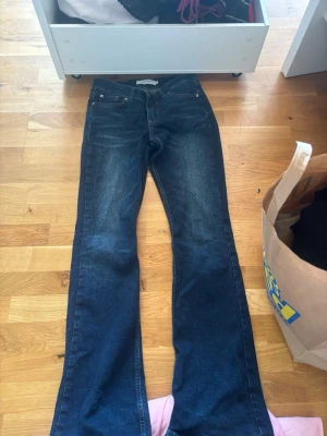 Mörkblå bootcut jeans Junkyard XS - Snygga mörkblå bootcut jeans från Junkyard i storlek XS. Jeansen har klassisk femficksmodell, normal midja och lätt utsvängda ben. Tillverkade i ett slitstarkt denimtyg med subtila slitningar för en cool look.