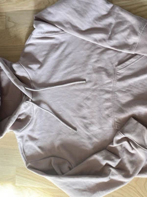 Ljusbeige rosa hoodie från H&M XS - Säljer en ljusbeige rosa hoodie från H&M i storlek XS. Hoodien har en klassisk huva med dragsnören och en stor magficka framtill. Tillverkad i mjukt bomullsmaterial som är skönt mot huden. Perfekt för en avslappnad och stilren look.