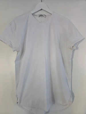 Vit t-shirt från Selected Homme - Vit t-shirt från Selected Homme med rund hals och korta ärmar. Tillverkad i mjuk bomull och har en enkel, clean design som är lätt att matcha med olika outfits. Perfekt för dig som gillar basic och stilrent.