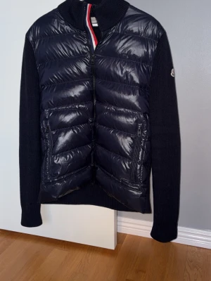 Moncler cardigan  - Säljer nu min Moncler cardigan som är i storlek XL (passar L). Jackan är sparsamt använd men har lagade flaws som syns i bilden, i övrigt är den i bra skick! Jackan är självklart äkta och det bekräftas av tagsen. 