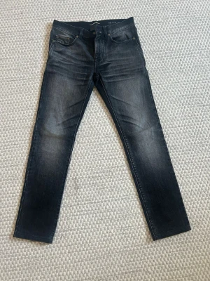 ysl jeans  - Snygga svarta jeans från Saint Laurent med en unik patch på bakfickan där det står 'Saint Laurent Université'. Jeansen har raka ben och klassisk femficksdesign. Materialet är denim med en lätt tvättad look och diskreta slitningar.  Köpte nyss här på Plick till sonen, men tyvärr var de för små, så säljer de därför igen. 