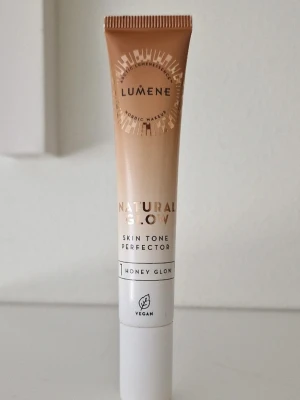 Lumene Natural Glow Bronzer Honey Glow - Lumene Natural Glow Skin Tone Perfector i nyansen Honey Glow ger en fräsch, solkysst look. Tuben är beige och vit med guldiga detaljer och innehåller 20 ml. Produkten är vegansk och har en lätt, krämig formula som smälter in i huden för naturlig lyster. Endast testad.