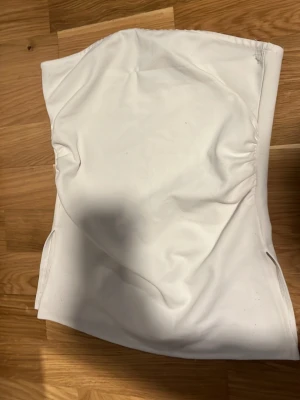 Vit bandeau tubtopp från 157 - Säljer en enkel och stilren vit bandeau tubtopp från 157. Toppen är axelbandslös och har en mjuk, stretchig passform som sitter snyggt på kroppen. Perfekt att matcha med jeans eller kjol för en clean look.
