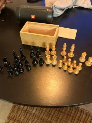 Schackpjäser i trä med förvaringslåda - Säljer ett komplett set schackpjäser i trä, både svarta och ljusa, tillsammans med en enkel trälåda för förvaring. Pjäserna har klassisk form och är tillverkade i polerat trä. Perfekt för dig som gillar strategispel och vill ha ett snyggt set hemma.