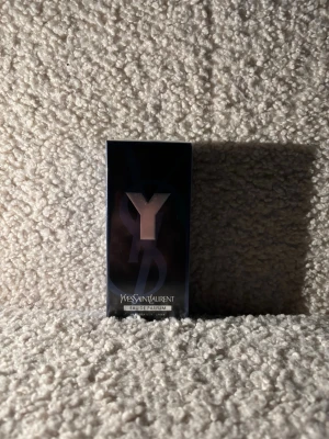 Yves Saint Laurent Y Eau de Parfum oöppnade  - Y Eau de Parfum från Yves Saint Laurent kommer i en elegant, mörkblå rektangulär kartong med en stor silverfärgad Y-logga på framsidan. Förpackningen har en lyxig känsla och passar perfekt för dig som gillar exklusiva dofter.
