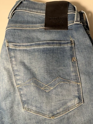 Ljusblå jeans från Replay Hyperflex - Snygga ljusblå jeans från Replay Hyperflex med klassisk femficksdesign och coola kontrastsömmar på bakfickan. Jeansen har en skön stretchig känsla och läderpatch med logga i midjan. Perfekta för en avslappnad och trendig look. 31/32