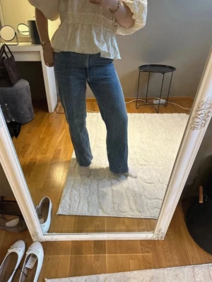 Blå raka jeans med normal passform - Säljer ett par klassiska blå jeans med rak passform och hög midja. Går till under naveln. Storlek 28/32