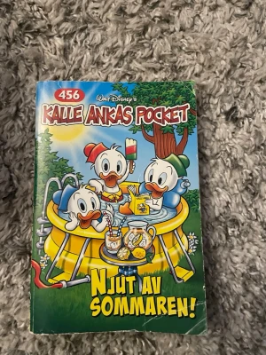 Kalle Ankas Pocket 456 Njut av sommaren - Kalle Ankas Pocket nummer 456 med titeln 'Njut av sommaren!' bjuder på 256 sidor fulla av somriga äventyr med Kalle, Knattarna och andra klassiska Disneyfigurer. Färgglad pocketbok med tecknade omslag i blått, grönt och gult. Perfekt för dig som gillar humor och spänning.