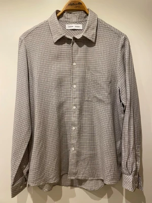 Gråvit rutig skjorta Samsoe Samsoe - Saryan J Shirt - Stilren gråvit rutig skjorta från Samsoe Samsoe. Väldigt bra skick, använt bara en gång (blev fel storlek). Nypris 1400kr. Storlek M. 