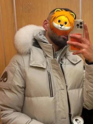 Beige Grå dunjacka Moose Knuckles M - Snygg beige dunjacka från Moose Knuckles med stor vit pälskrage och klassisk logga på ärmen. Jackan har flera fickor, dragkedja och tryckknappar framtill. Perfekt för kalla vinterdagar och riktigt varm. Köpt från Johnells och kvitto finns!