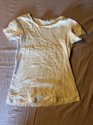 Vit basic t-shirt från tribute - En klassisk vit t-shirt i mjuk bomull. Modellen har rund halsringning och korta ärmar, perfekt för en clean och enkel stil. Passformen är normal och tyget är tunt och skönt mot huden.