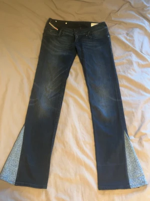 Mörkblå bootcut lowaist jeans med leoparddetalj - Snygga mörkblå bootcut lowaist jeans från diesel med leopardmönstrade kilar i bensluten som jag har sytt själv. Jeansen har dekorativa nitar på bakfickorna och klassisk femficksdesign. Materialet är denim med stretch för skön passform.