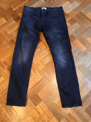 Mörkblå slim/ straight fit jeans från Jack and Jones  - Snygga mörkblå slim fit jeans med klassisk femficksdesign och lätt slitna detaljer framtill. Jeansen har normal midja och raka ben, perfekta för en avslappnad men stilren look. Skriv vid funderingar ! 