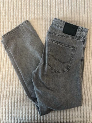 Grå raka jeans från jack & jones - Snygga grå jeans från jack & jones med rak passform och klassisk femficksdesign. Jeansen är i modellen chris/loose. Storlek W31 och L32.