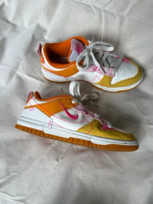 Nike Dunk Low i färgglad mix - Nike Dunk Low sneakers i vitt, gult, orange och rosa med rosa swoosh. Använda ett fåtal gånger.