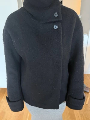 Höstjacka - Säljer denna fina höstjacka/kappa som är lite varmare i materialet. Från arket och i fin kvalitet. Storlek 34 men ganska stor i storleken så är mer som en 36/38 skulle jag säga. Man kan ha jackan öppen, knäppt eller knäppa ända upp i halsen. Går inte ur mode utan kan stylas till typ allt. (Ska rollas innan jag skickar den). Nypris var ca 2000 kr. Tar bud. Kolla gärna in mina andra annonser så samfraktar jag! 😁