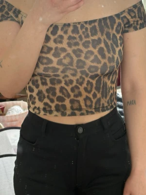 Leopardmönstrad offshoulder croppad topp - Snygg croppad topp med leopardmönster och offshoulder-design. Toppen har en tight passform och korta ärmar. 