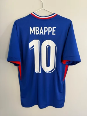 France 2024 Home - #10 Mbappe - size M - 9/10 - Frances home kit used during the Euros 2024 in Germany lead by their captain number 10 Kylian Mbappe. France uses a blue base combining their flags colors in the collar in a v-neck style and red triangular shapes on the sleeve cuffs 🔵  Condition: 9/10. Excellent!  Size: M  Product code: FJ1259-452