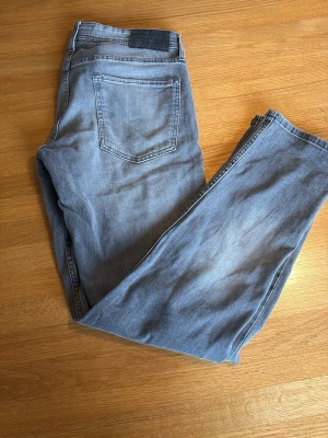 Grå jeans från Stock & Hank - Snygga grå jeans från Stock & Hank med klassisk femficksmodell och raka ben. Jeansen har en diskret tvättad look och är tillverkade i mjukt denimtyg som ger en avslappnad känsla. Perfekta för dig som gillar stilrena och enkla jeans.