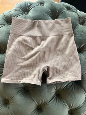 Beige ribbade seamless cykelshorts - Säljer ett par beige ribbade seamless cykelshorts från H&M Move. De har hög midja och är tillverkade i ett stretchigt material som sitter skönt på kroppen. Perfekta för träning eller chill dagar. Snyggt ribbat mönster och kort modell.