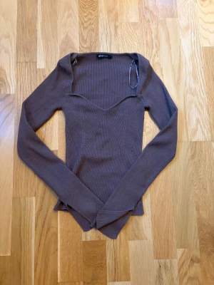 Brun ribbad topp från Gina Tricot - Säljer en brun långärmad topp från Gina Tricot i ribbat material. Toppen har en snygg v-ringad skärning och sitter tight. Perfekt att styla med jeans eller kjol för en trendig look.