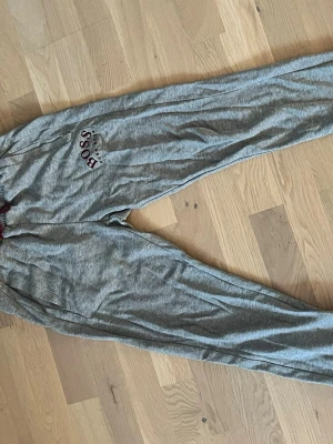 Hugo boss byxor - Mysiga grå loungewearbyxor från BOSS med resår i midjan och rödvit HUGO BOSS-logga. Byxorna har fickor på sidorna och är perfekta för chill hemma. Mjukt material som känns skönt mot huden.