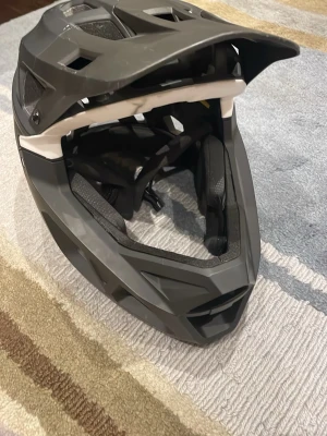 Svart och vit cykelhjälm med skärm - Säljer en svart och vit cykelhjälm med skärm och heltäckande hakskydd. Hjälmen har flera ventilationshål och vadderad insida för extra komfort. Perfekt för dig som gillar downhill eller BMX.              