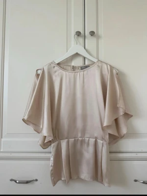 Champagnefärgad satinblus - Elegant blus i skimrande champagnefärgad satin från ASOS. Perfekt för sommaren, skriv vid frågor.