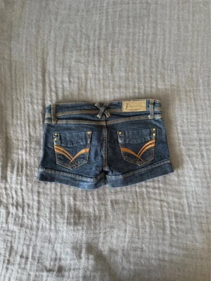 Lågmidjade jeansshorts  - Snygga blå denimshorts från Stradivarius med låg midja och dekorativa sömmar på bakfickorna. Perfekta för varma sommardagar.