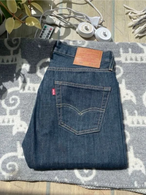 Mörkblå Levi's jeans med rak passform - Dem är helt nya aldrig, har aldrig varit använd.Säljer ett par klassiska mörkblå jeans från Levi's med rak passform. Jeansen har tydliga kontrastsömmar, fem fickor och den ikoniska läderpatchen bak i midjan. Perfekta för en stilren och tidlös look.