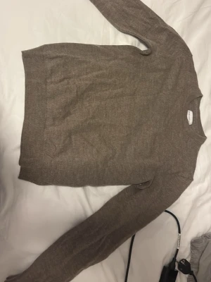 These glory days - Säljer en enkel och stilren brun stickad tröja med rund hals. Tröjan har långa ärmar och är gjord i mjuk ullblandning, perfekt för kyligare dagar. Passar till både jeans och chinos för en avslappnad look.