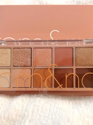 Rom&nd ögonskuggspalett 01 Pampas Garden - Rom&nd Better Than Palette 01 Pampas Garden med 10 nyanser i varma toner som beige, korall, brunt och guld. Paletten innehåller både matta och skimrande skuggor, perfekt för att skapa olika ögonlooks. Snygg och kompakt design med genomskinligt lock.