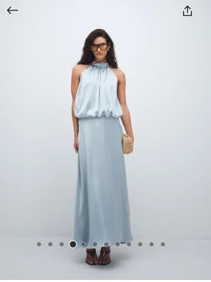 Ljusblå långklänning från Gina Tricot - Oanvänd elegant ljusblå långklänning i satin från Gina Tricot med halterneck och lös passform upptill. Klänningen är helt oanvänd med etiketter kvar. 