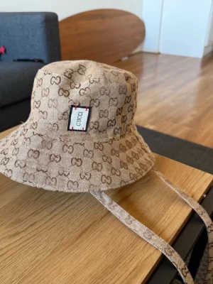 2-in-1 Reversible Designer Style Bucket - Selling this beautiful, high-quality bucket hat. The best part? It's fully reversible! E) • Exterior: Iconic monogram print on premium canvas material. • Interior: Soft, plain beige lining-wear it inside-out for a completely different look. • Details: Comes with long adjustable straps that can be tied or left hanging for a trendy look. • Quality: Excellent craftsmanship, sturdy stitching, and beautiful fabric texture. Carefully stored in a smoke-free home. Fast shipping guaranteed!