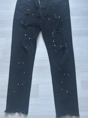 Slim fitt jeans  - Ett para svarta slim fitt jeans med vita färg duttar.