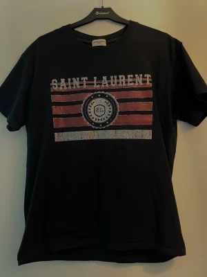 Saint Laurent t shirt - Tja! nu säljer jag denna riktigt feta t shirt från varumärket Saint Laurent, storleken S och skicket är mycket bra. Det kan se ut som att t shirten är solblekt osv men designen på t shirten ska vara så. Skicka Pm vid övriga frågor. 🪙