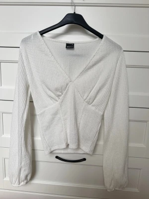 Vit långärmad topp – Gina Tricot - Fin vit långärmad topp från Gina Tricot i storlek XS. Strukturerat tyg och figursydd modell med V-ringning som ger en smickrande passform. Enkel men väldigt snygg bas-topp som passar till allt. Storlek: XS Skick: Mycket bra Färg: Vit
