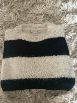 Randig stickad tröja från vero Moda  - Säljer en stickad tröja från vero Moda med breda svarta och vita ränder. Tröjan har rund halsringning och är gjord i ett mjukt, fluffigt material som känns riktigt cozy. Perfekt för lager-på-lager och chill dagar.