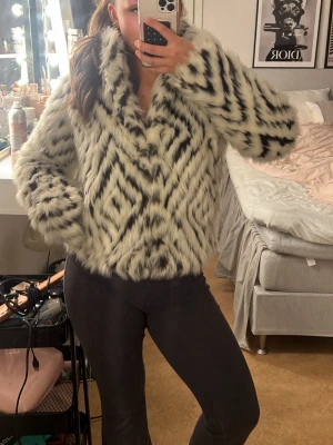 Vit och svart mönstrad pälsjacka - Säljer en fluffig pälsjacka med vit bas och svarta zigzag-mönster. Köpte jackan på Sellpy så den finns nog inte att få tag på någon annan stans. Säljs då jag har för många jackor💘