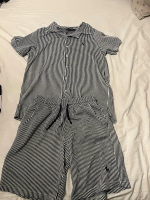 Randiga shorts från Polo Ralph Lauren - Blåvit randiga shorts från Polo Ralph Lauren i mjuk bomull. De har elastisk midja med snörning och klassisk broderad logga på benet. Perfekta för sommardagar och ger en chill vibe ihop med matchande skjorta.