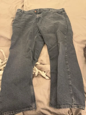 Blåa loose fit jeans - Säljer ett par blåa loose fit jeans med raka ben och klassisk femficksdesign. Jeansen har en knappgylf och är tillverkade i denim. Perfekta för en avslappnad och trendig stil.