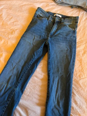 Blå jeans från Ellos, raka ben - Snygga blå jeans från Ellos i klassisk modell med raka ben och normal midja. Jeansen har fem fickor, bälteshällor och gul kontrastsöm. Perfekta för en avslappnad och stilren look.
