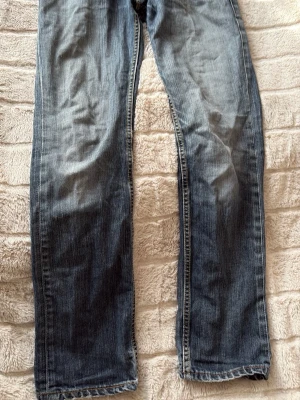 Levis 511 - Säljer ett par blå jeans med rak passform och snyggt tvättad look. Jeansen har klassiska sömmar och subtila slitningar för en avslappnad stil. Perfekta till vardags och passar till det mesta. 